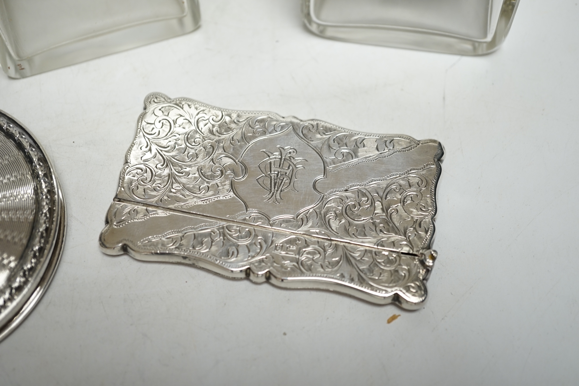 Five assorted silver topped glass toilet jars, a silver compact and an Edwardian engraved silver card case, Birmingham, 1902, 83mm.
